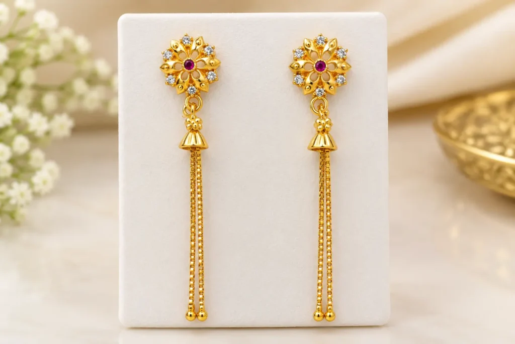 Gold plated floral jhumka earrings with ruby red stone, AD stones and long chain tassels