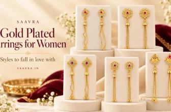 Saavra gold plated earrings with ruby-red stones and long chain tassels displayed on ivory jewellery stands.