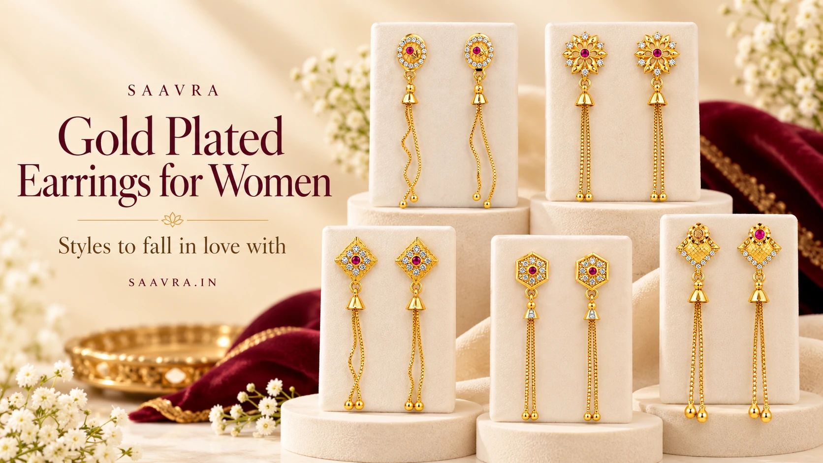 Saavra gold plated earrings with ruby-red stones and long chain tassels displayed on ivory jewellery stands.